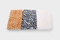 Folded fabric bundle: orange giraffe print, black zebra print, white plush backing