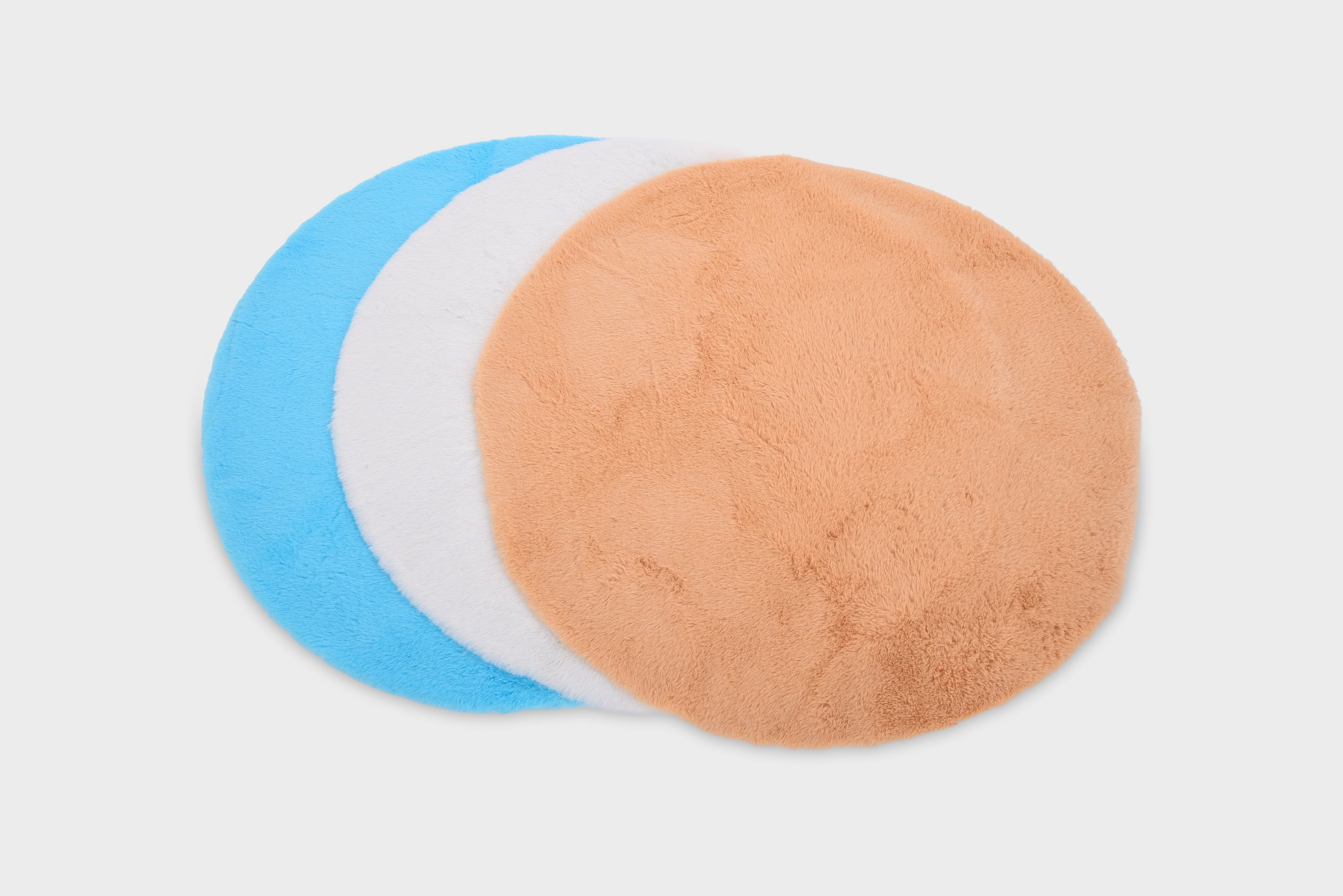 Set of three round plush fabric mats in blue, white, and tan