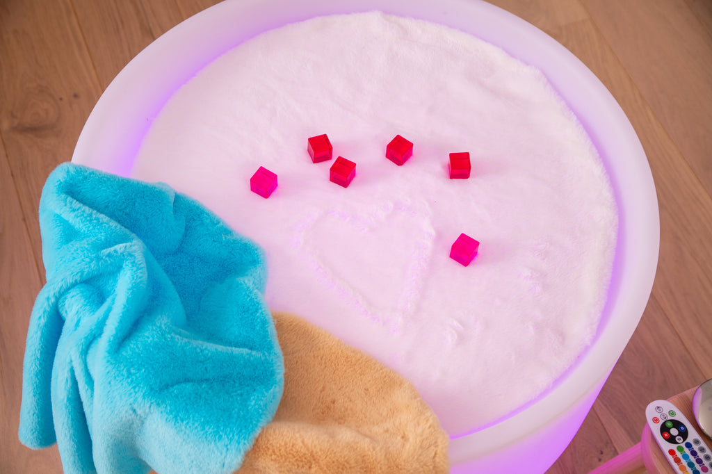 Close-up round sensory play mat with white plush, purple rim, and blue cloth