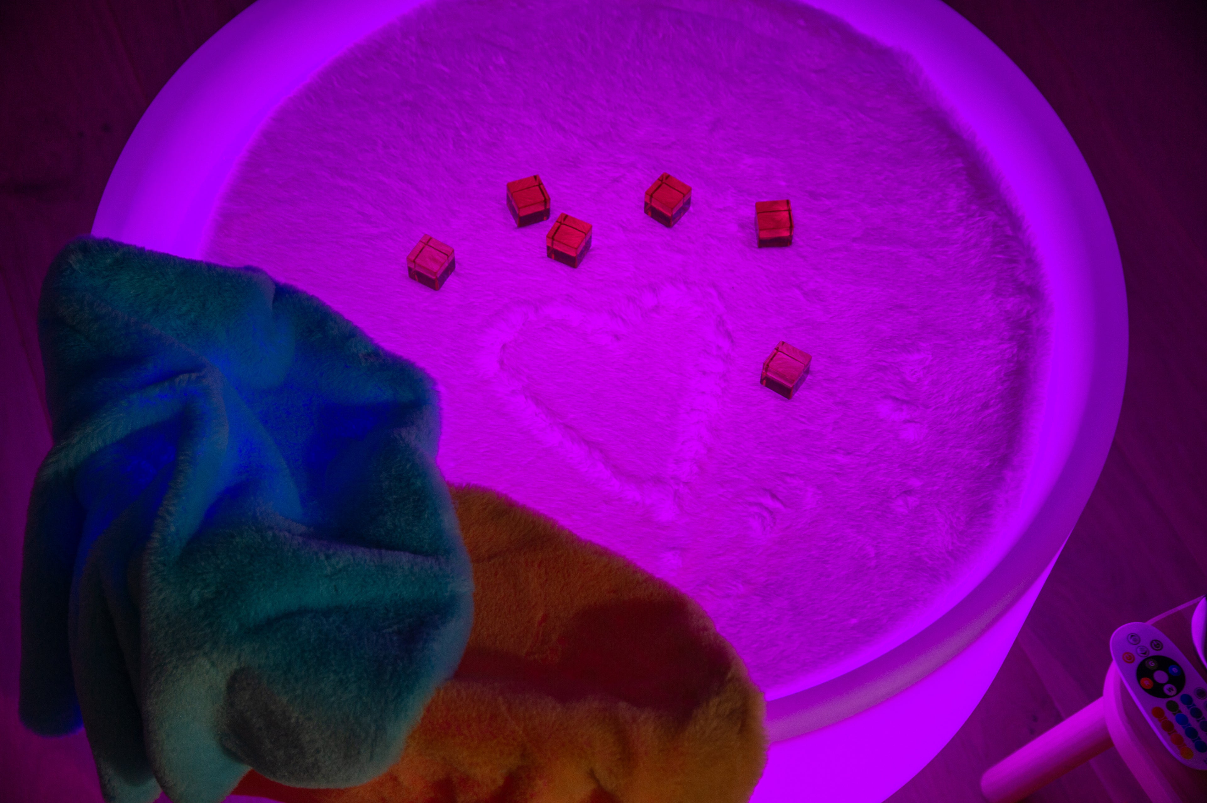 Round sensory play mat with bright blue center lighting, plush cover, and cube toys