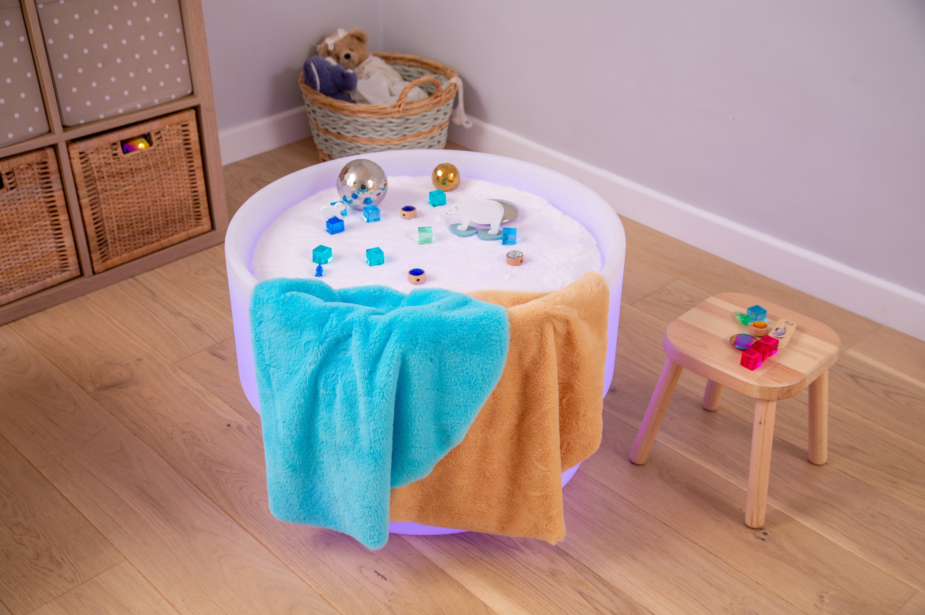 Round sensory play mat with blue and tan plush sides, blue textured center, and toys
