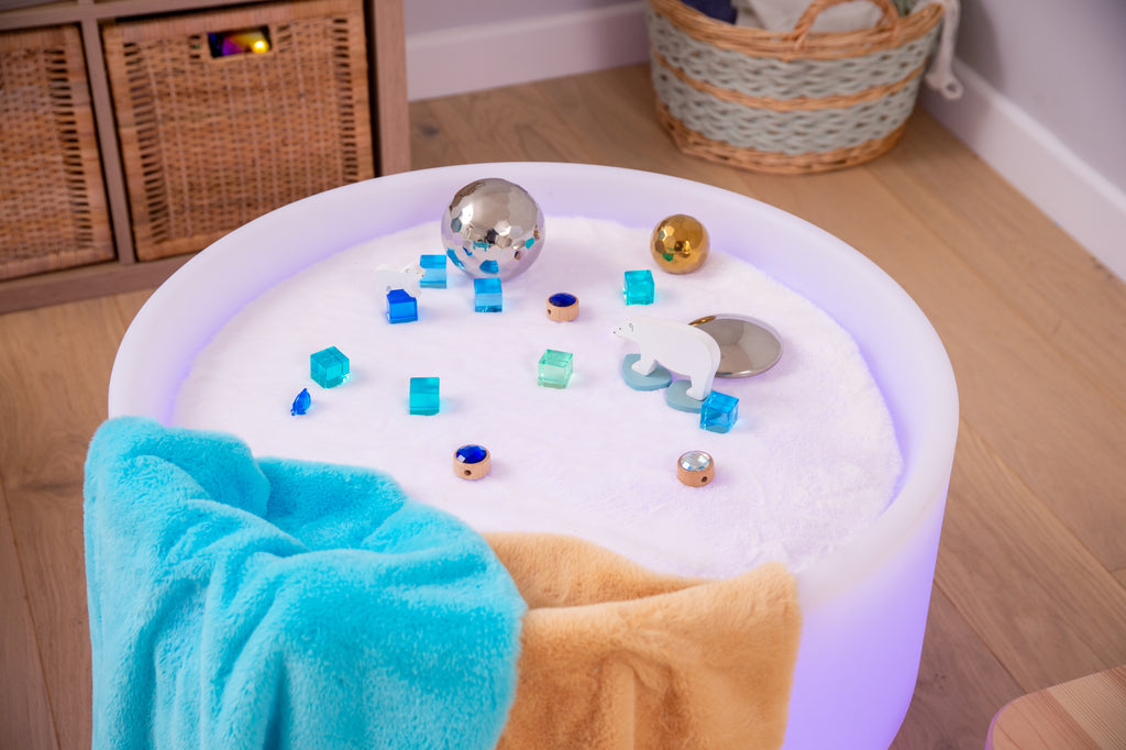 Round sensory play mat with blue textured center, plush sides, and metallic puzzle pieces