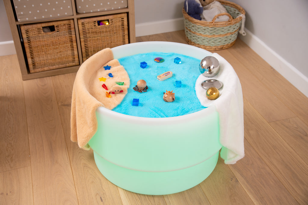 Round sensory play mat with blue textured center, white edge, and teal base