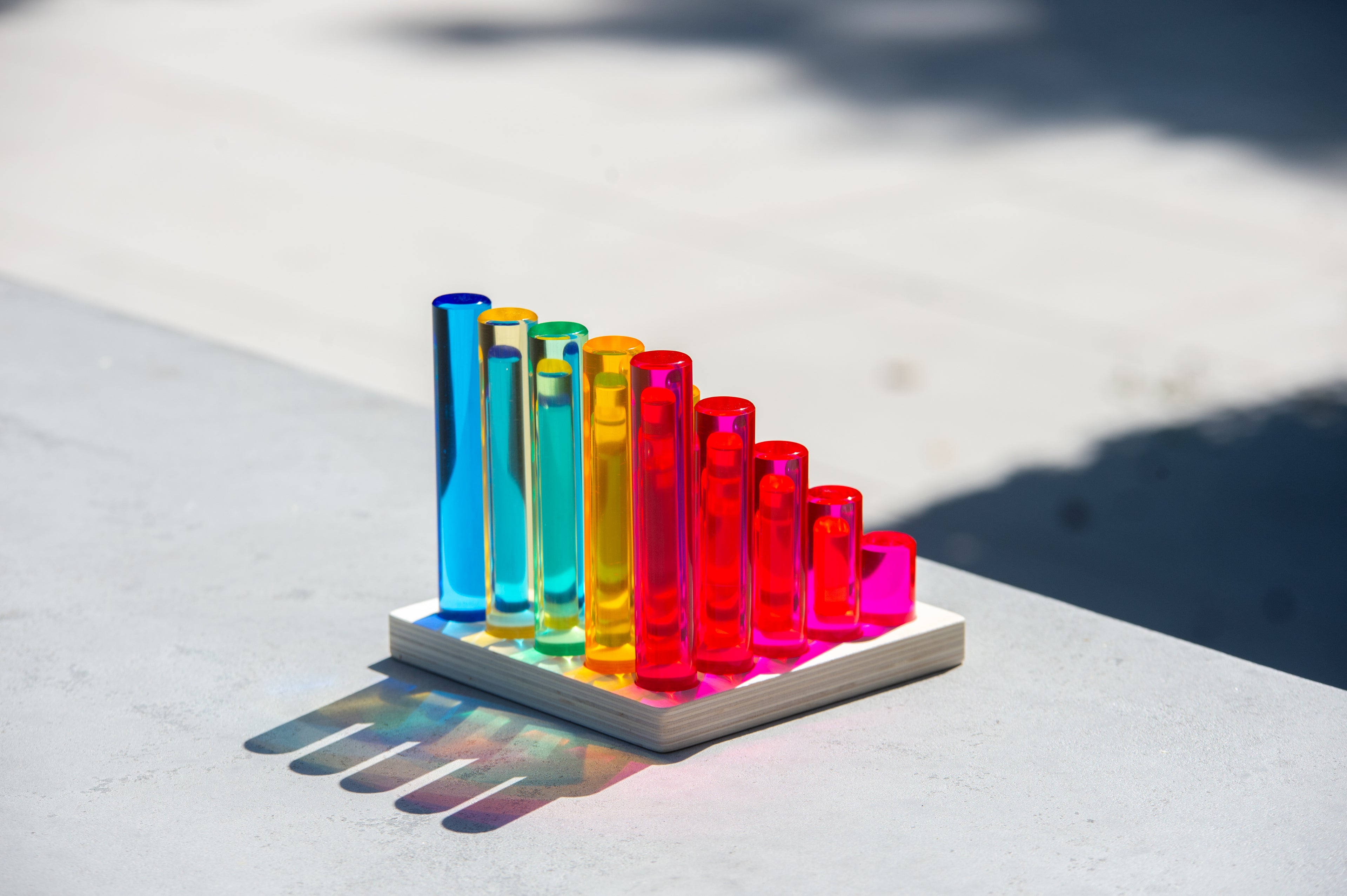 Gem column set on a square base tray with bright multicolor tubes outdoors