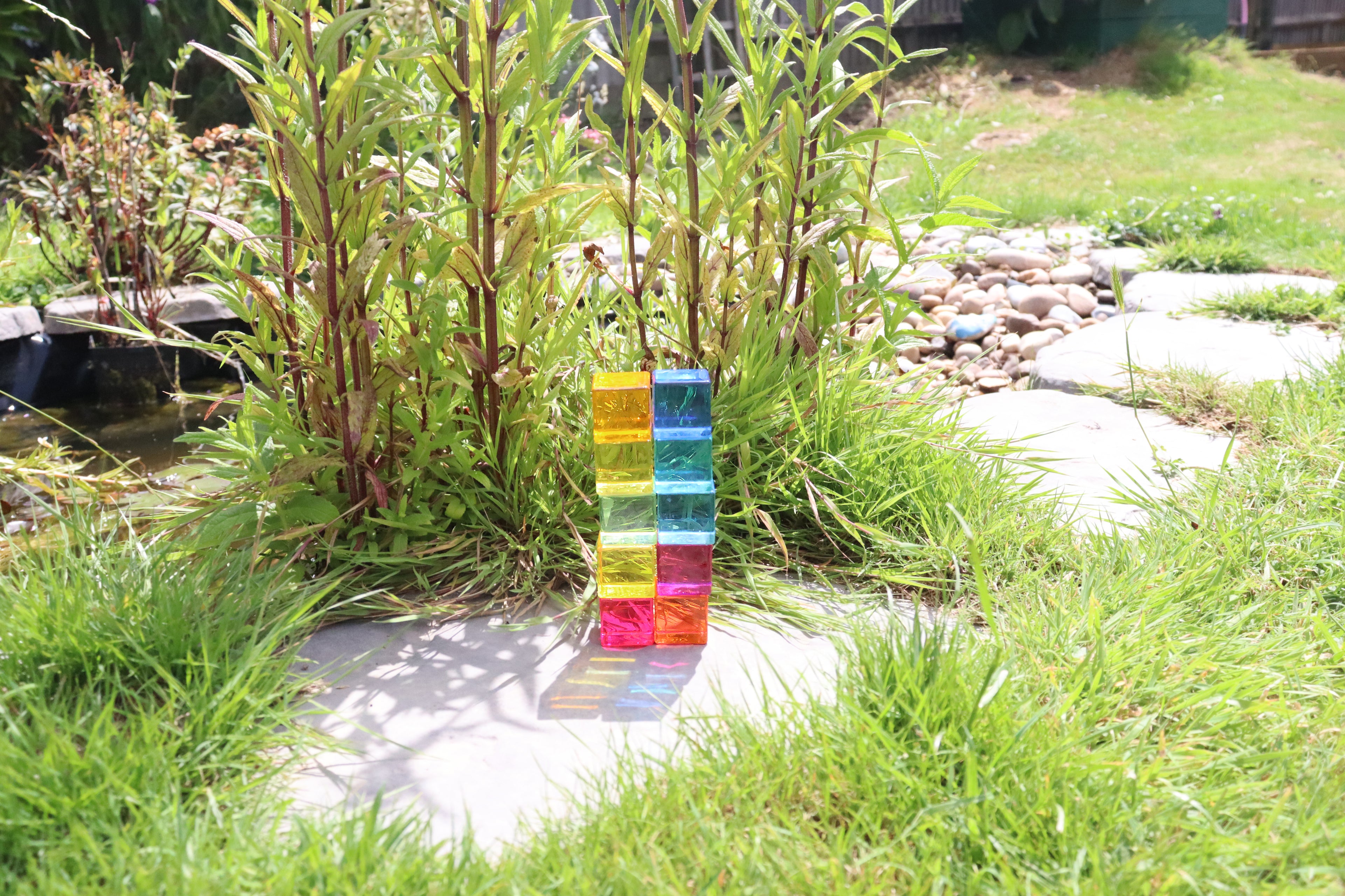 Stacked translucent gem cube blocks standing on a patio in the grass