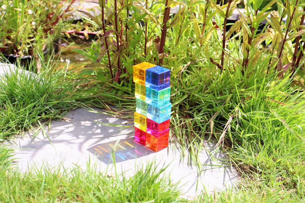 Tall stacked translucent gem cube blocks in a garden walkway