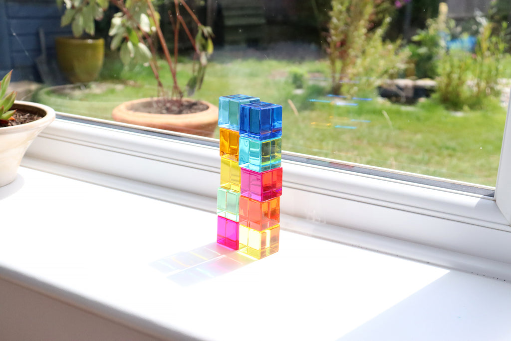 Stacked translucent gem cube blocks glowing in sunlight near a window
