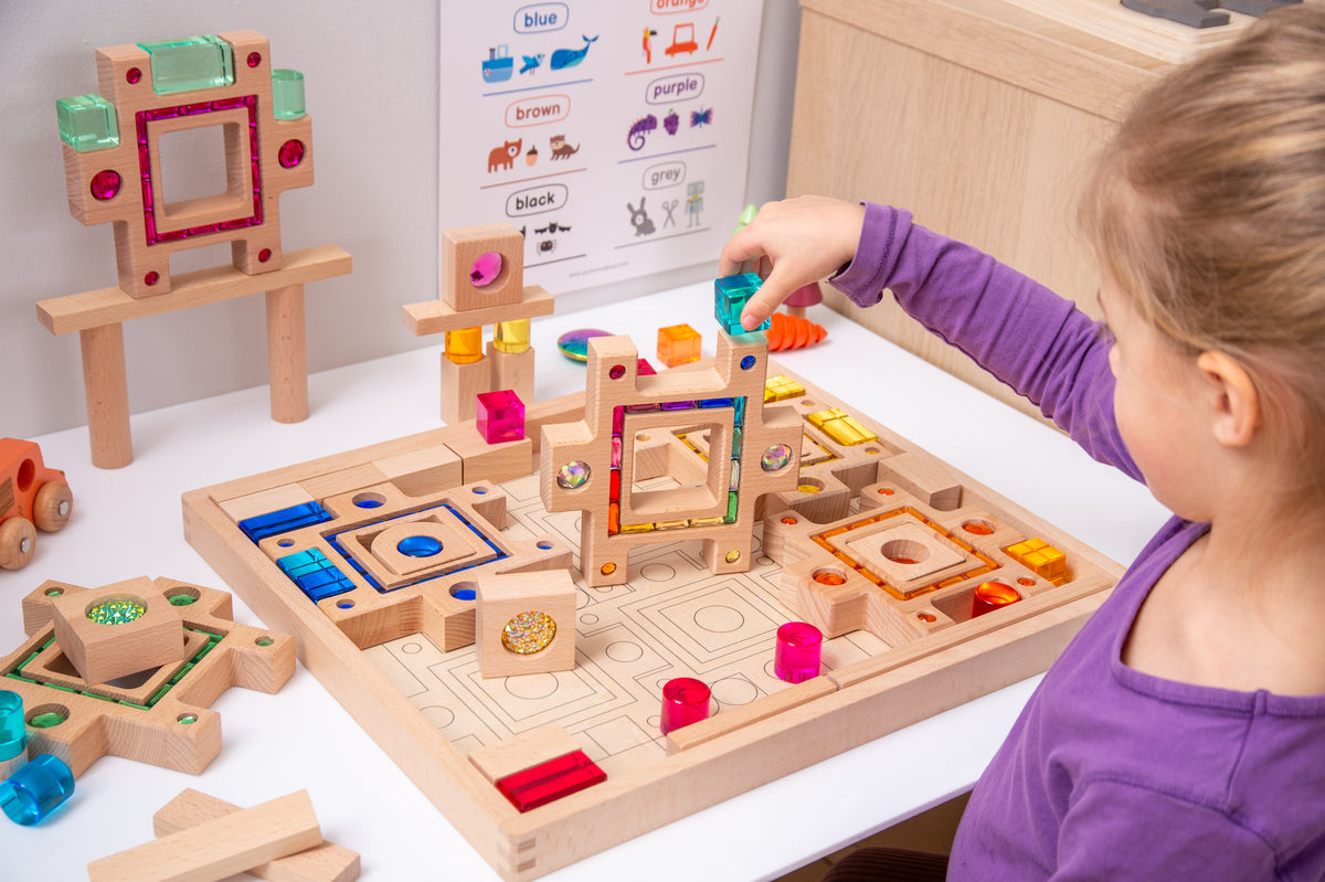 Wooden gem puzzle board with colored blocks and a child’s hand arranging tiles
