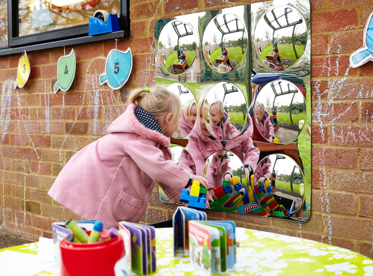 Acrylic 9-dome mirror panel mounted on brick wall with domes reflecting toys and kids