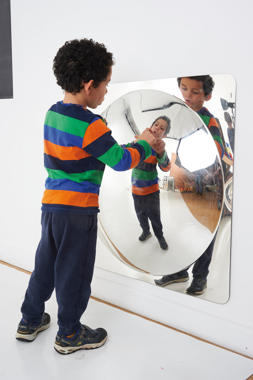 Oval acrylic mirror panel mounted on a wall with curved reflective glass surface