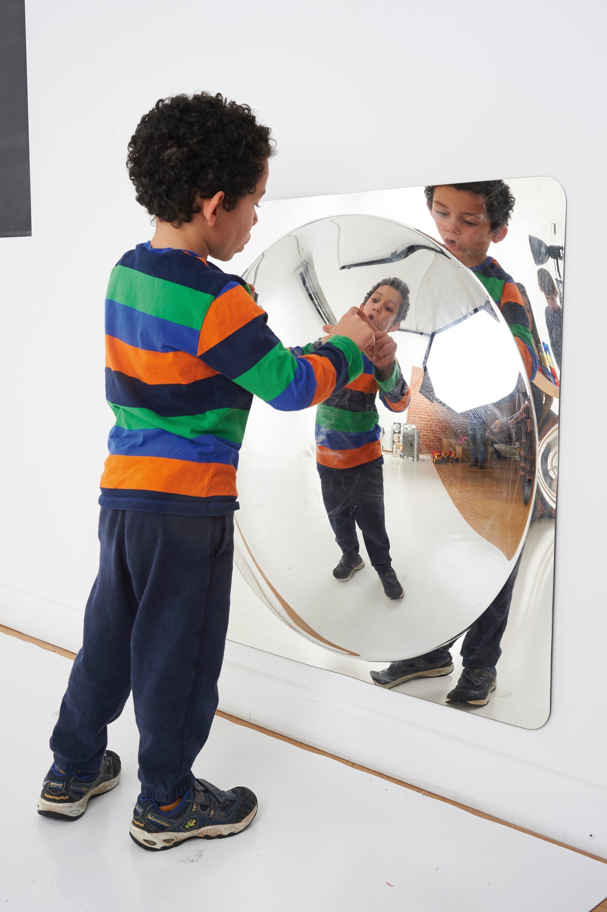Oval acrylic mirror panel mounted on a wall with curved reflective glass surface
