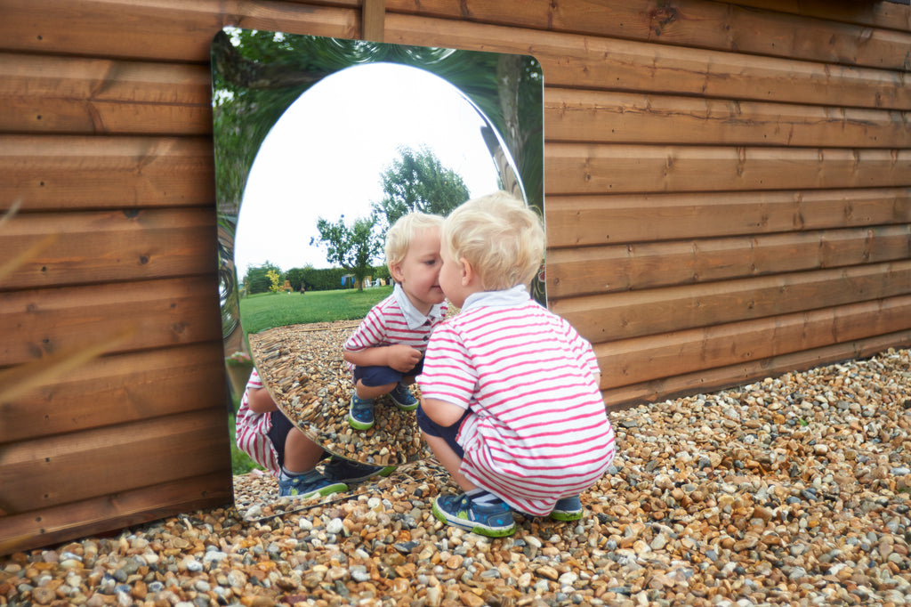 Acrylic dome mirror panel set into a wooden playhouse wall with curved reflective opening
