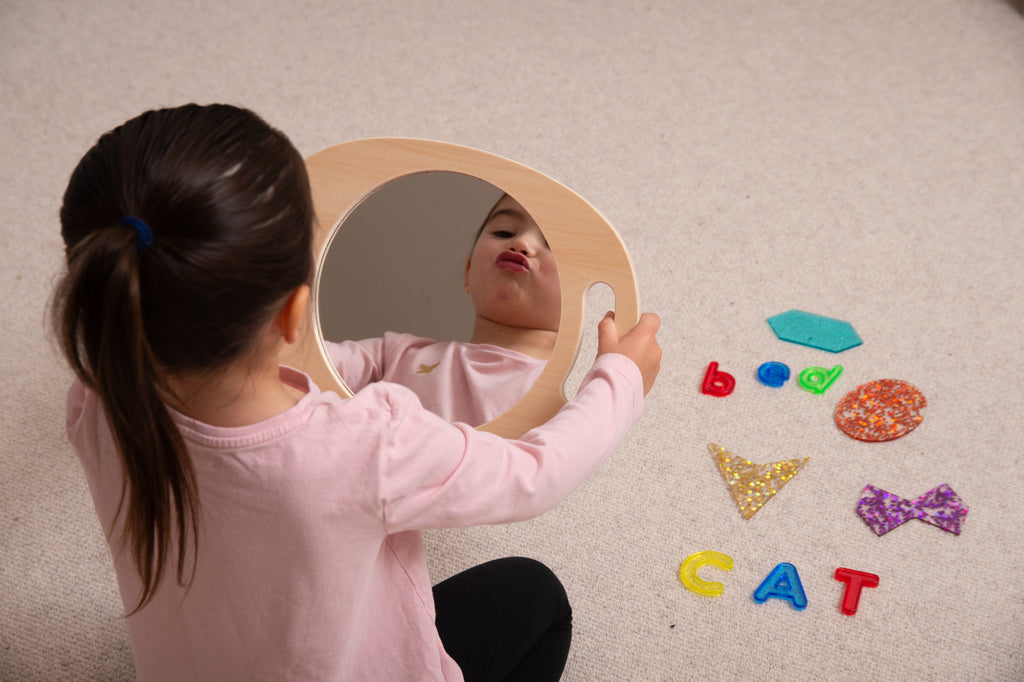 Light wood handheld round mirror with oval glass, child holding it during play