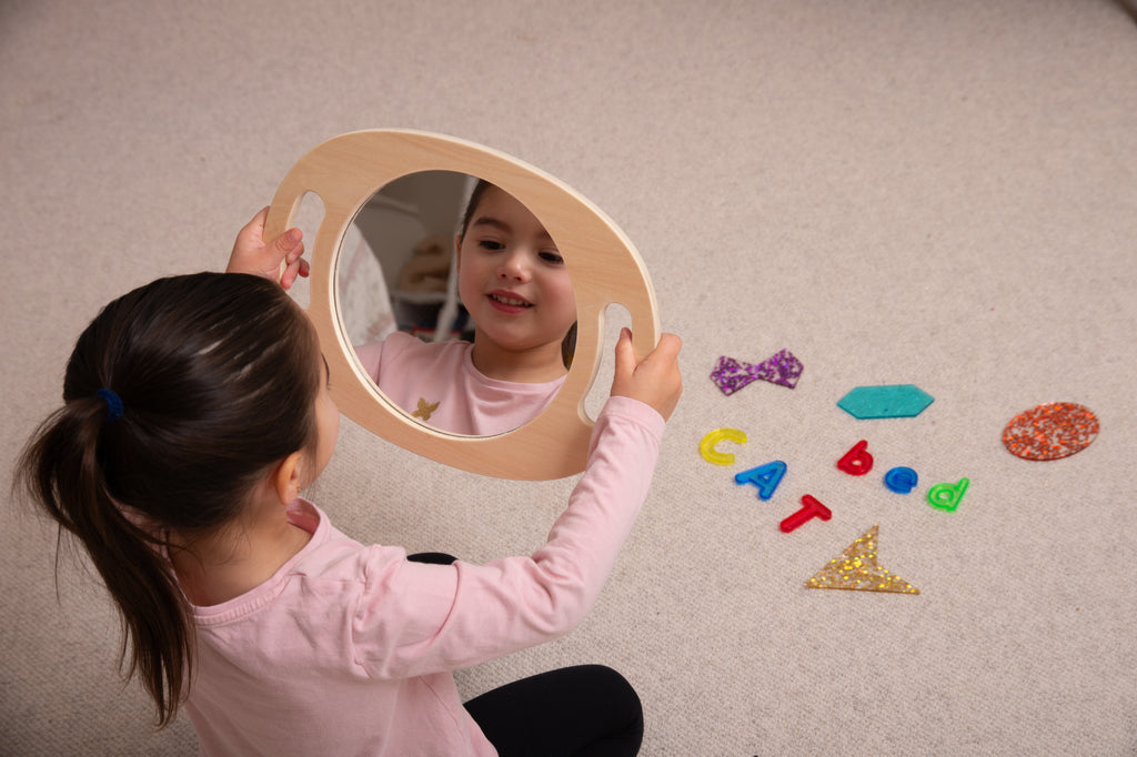 Light wood handheld round mirror with oval reflective glass, child looking into it