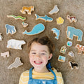 Colorful animal cutout shapes on felt fabric, with a smiling child nearby