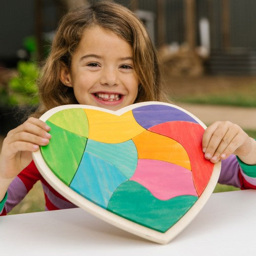 Heart-shaped multicolor board with curved rainbow-style segments, held by a child