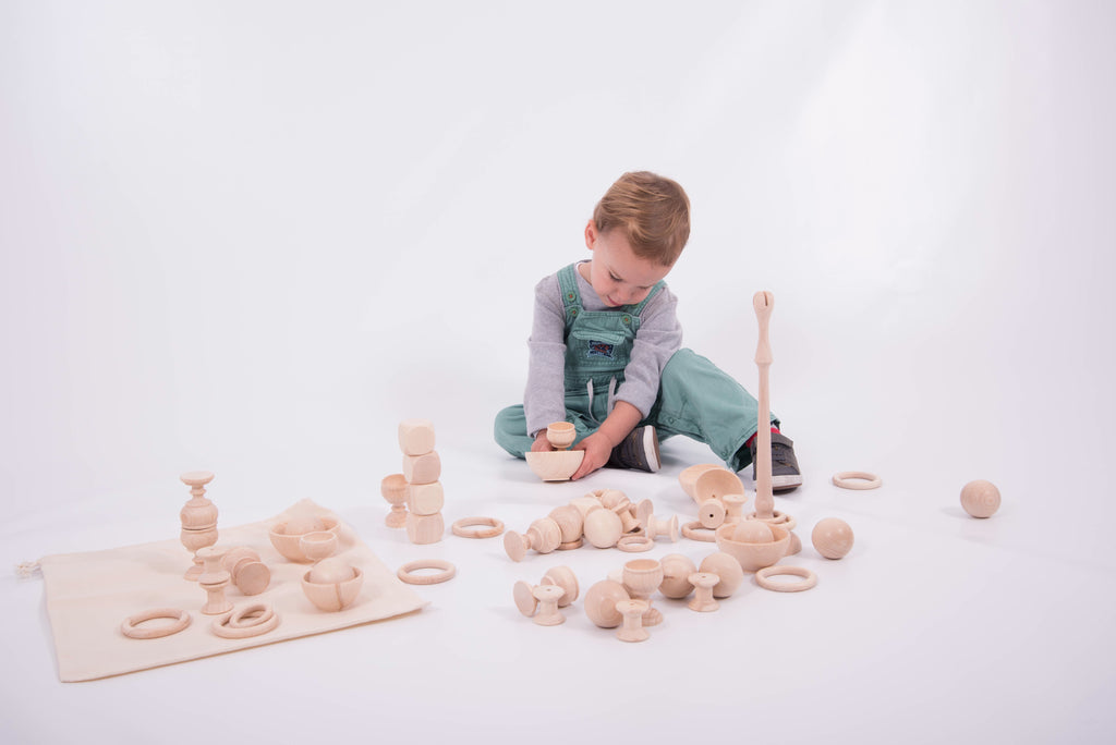 Wooden play starter set with stacked rings and towers; child arranging on play mat