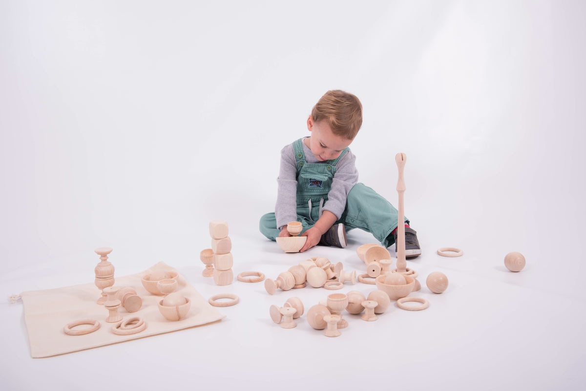 Wooden play starter set with stacked rings and towers; child arranging on play mat