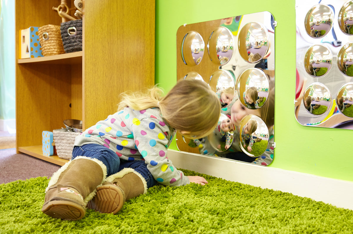 Large acrylic mirror panel with nine domed round mirrors showing toddler reflections