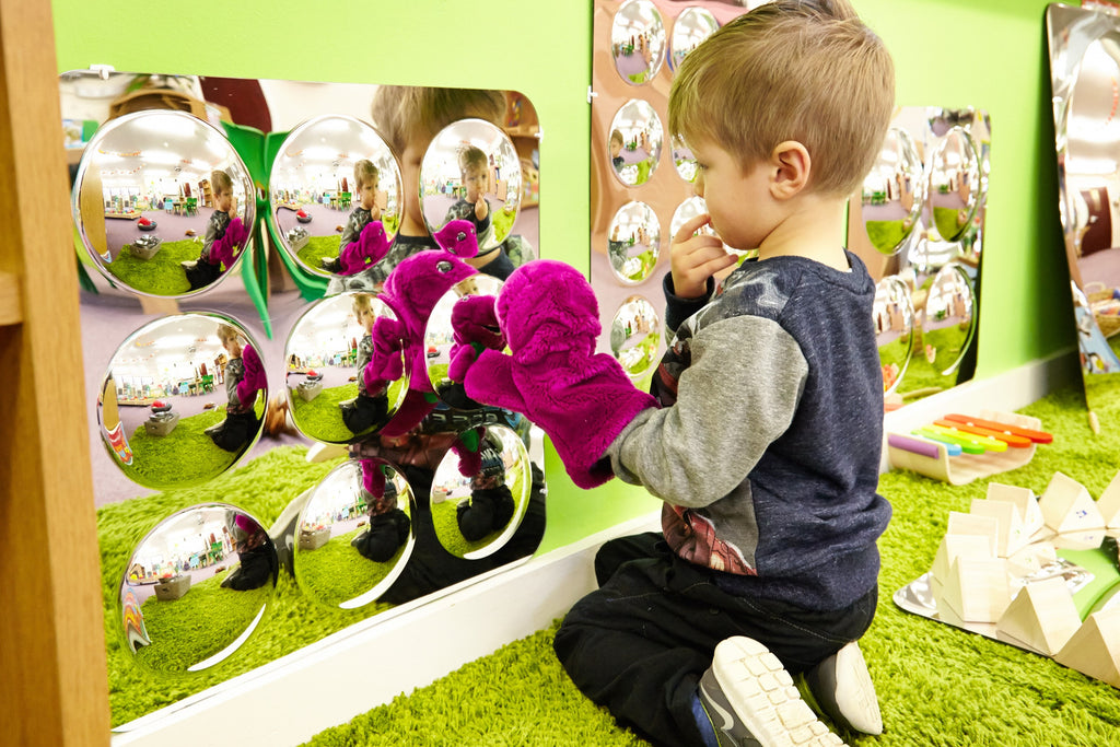 Large acrylic mirror panel with nine domed round mirrors reflecting indoor scene