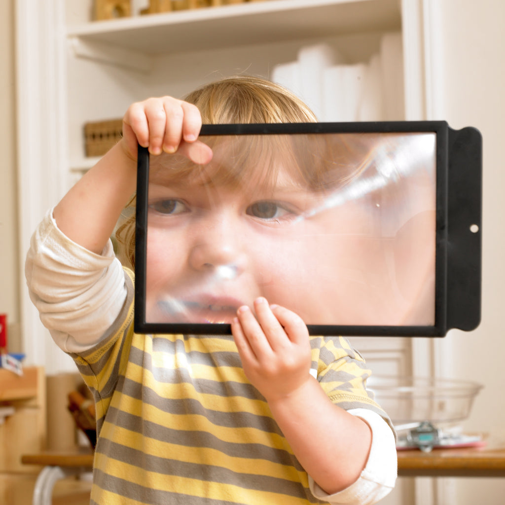 Black rectangular sheet magnifier held to a child’s face for close-up viewing