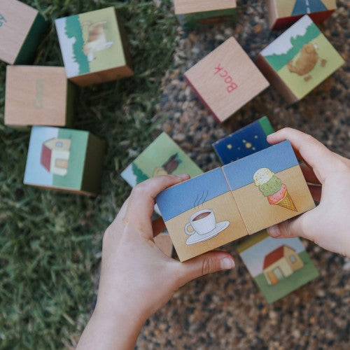 Hands holding a set of illustrated opposite blocks learning toy