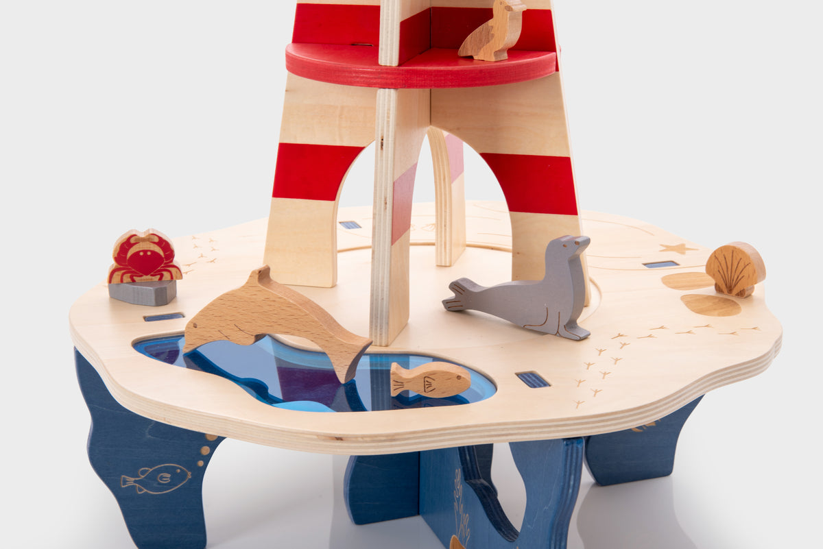 Wooden lighthouse playset with striped tower and wooden sea animals on curved platform