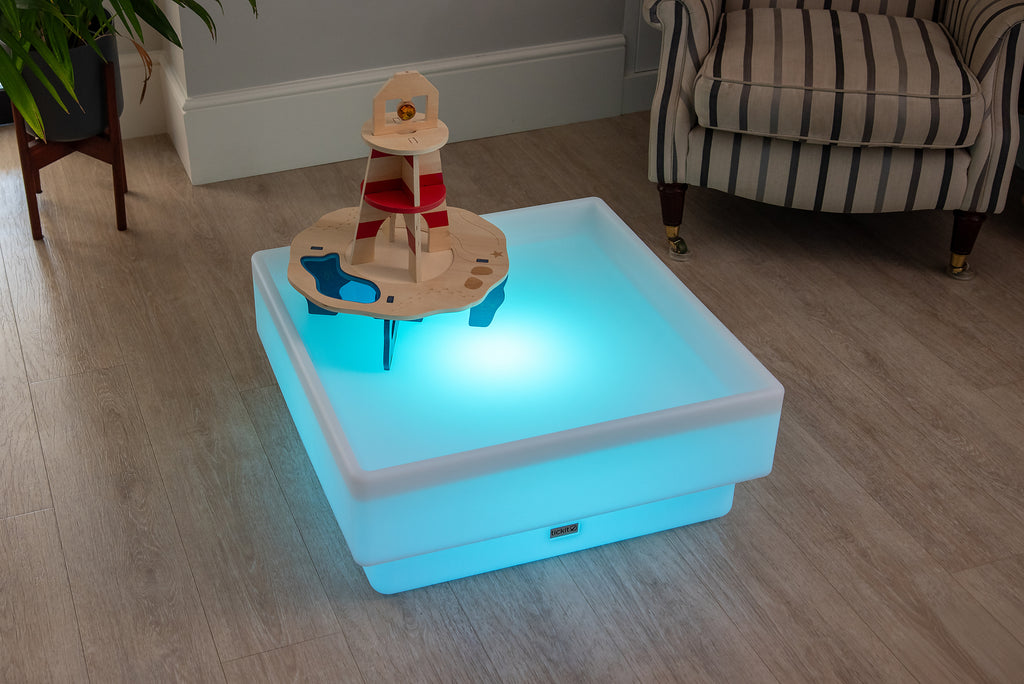 Light-up wooden water play tray with lighthouse tower and sea-themed pieces on top