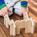 Wooden block building set with child hands and legs in colorful pajamas