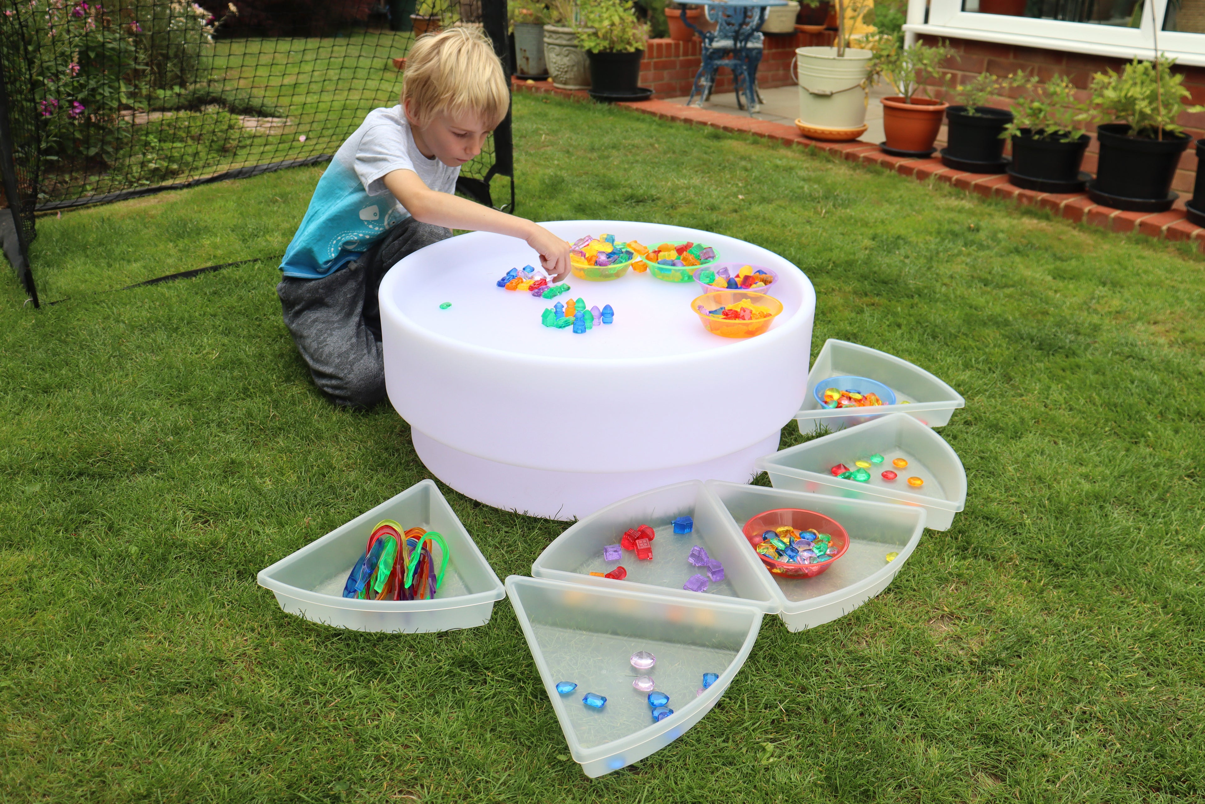 Kid playing with white bead sorting bowl and open multi-compartment tray