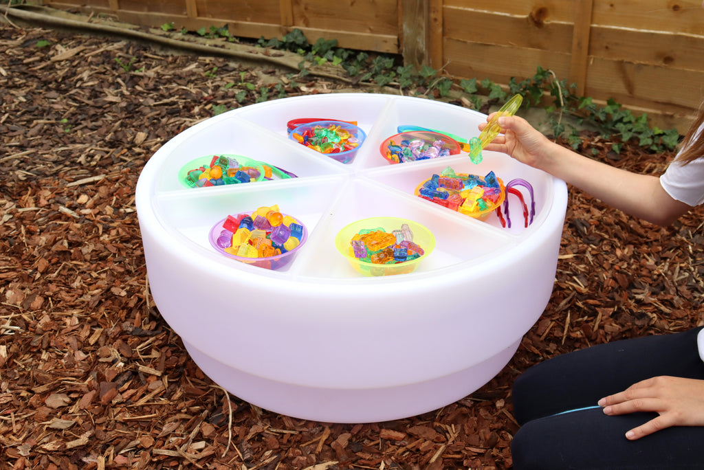 White round sorting tray on grass with separated color compartments