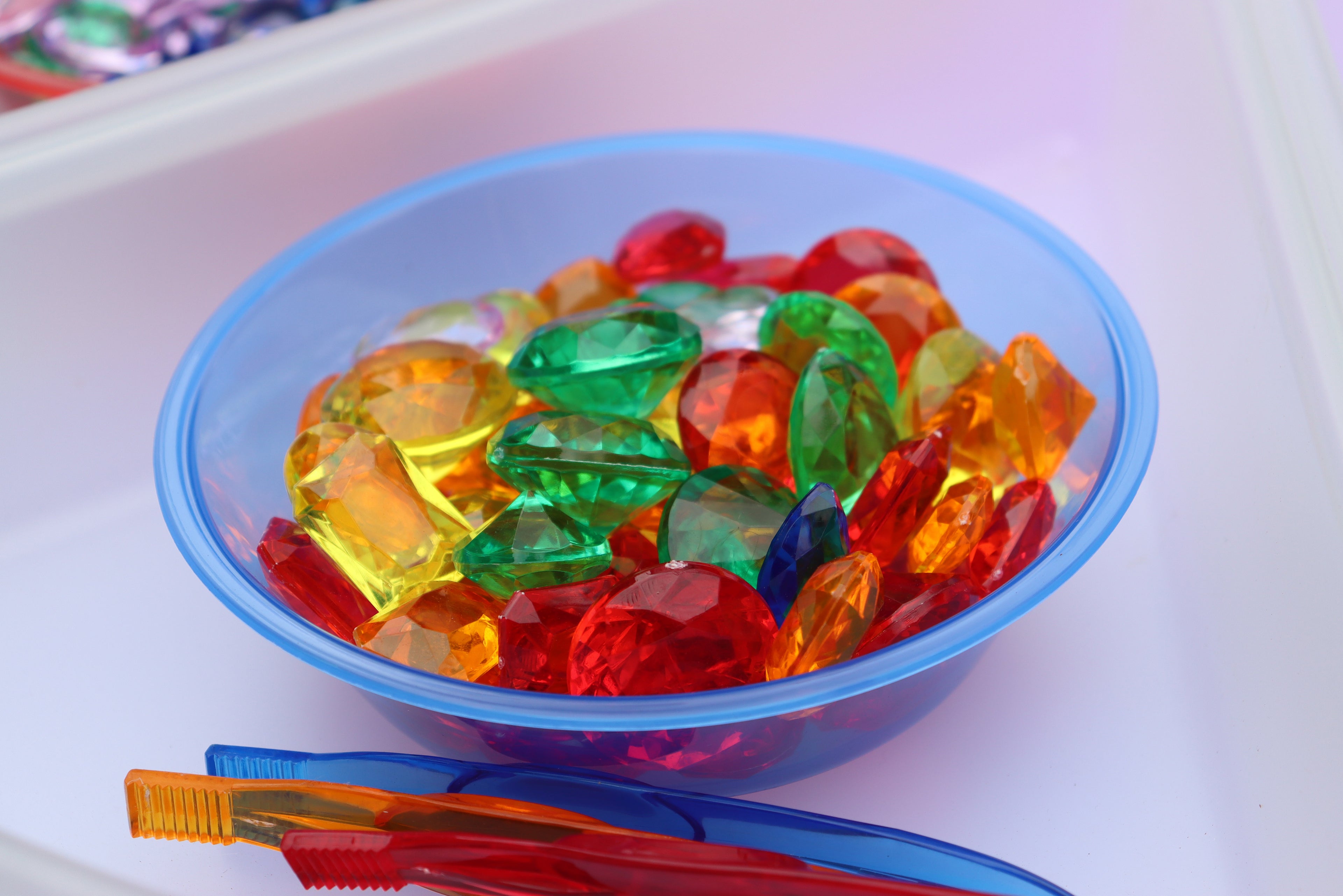 Clear bowl filled with colorful plastic sorting beads and gems