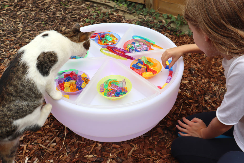 White outdoor sorting bowl with multicolor beads and kid hands