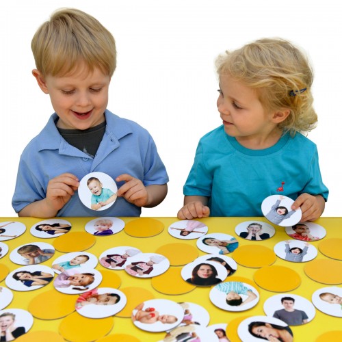 Children holding emotion face cards from a matching pairs memory game