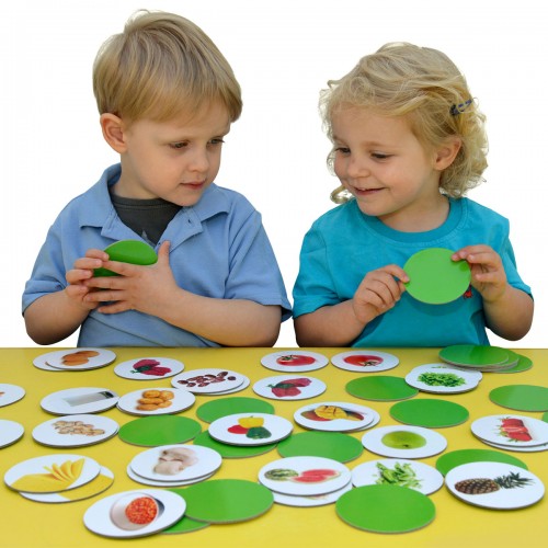 Healthy foods memory game with matching picture cards on green board, kids holding cards