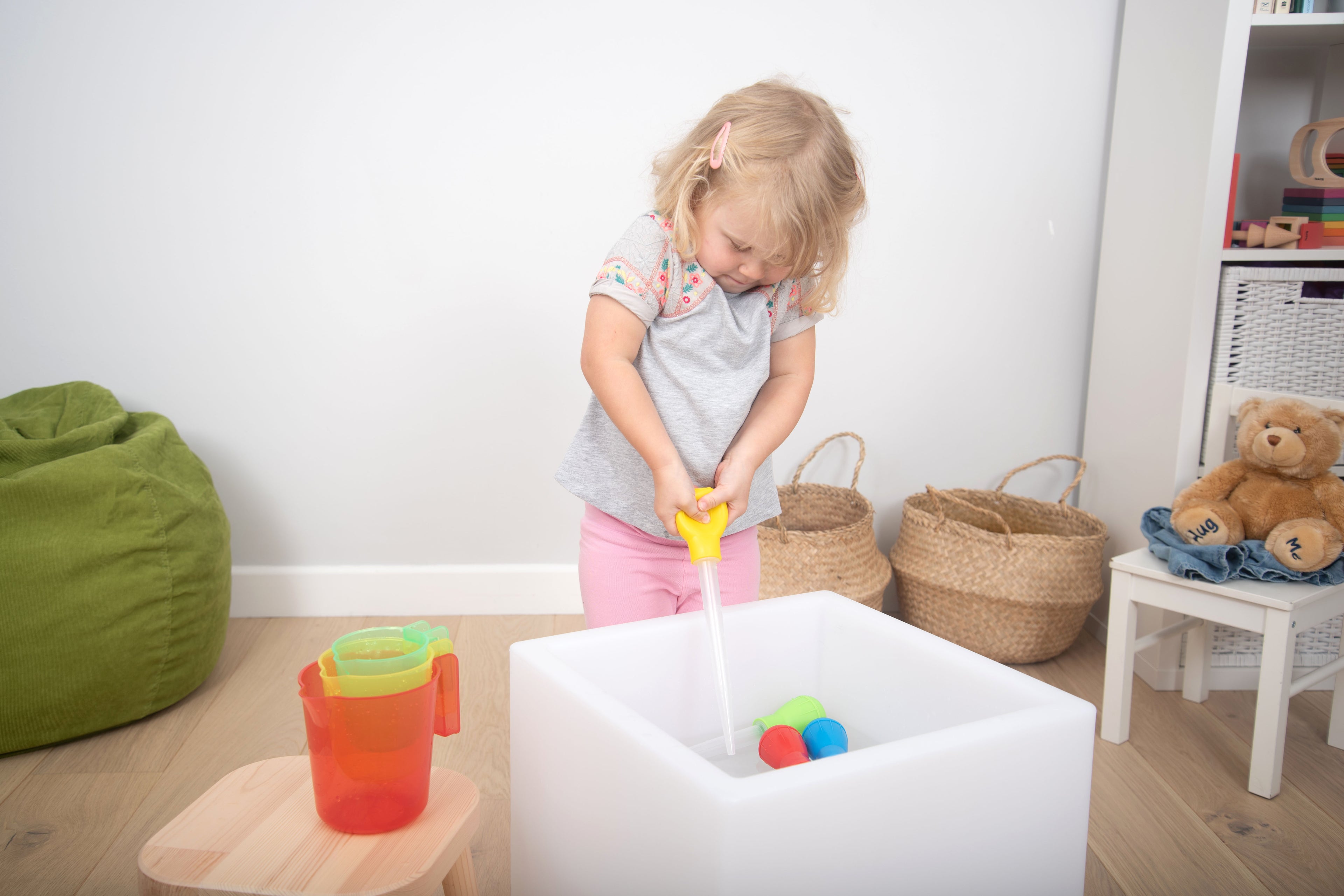 Measuring pipettes set in use: yellow pipette pouring into white tub with colored pieces