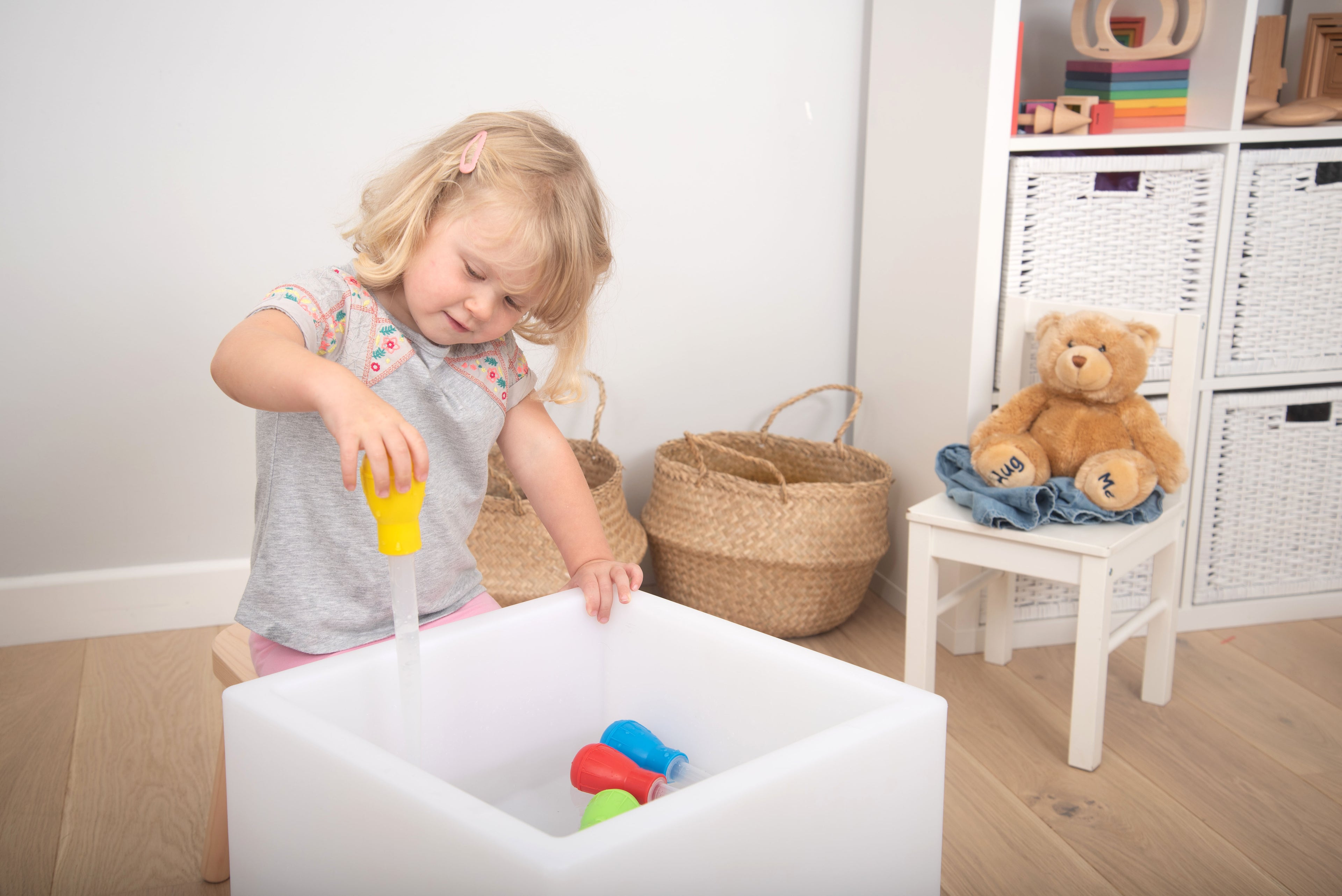 Measuring pipettes set in use: yellow pipette dipping into white tub with toys