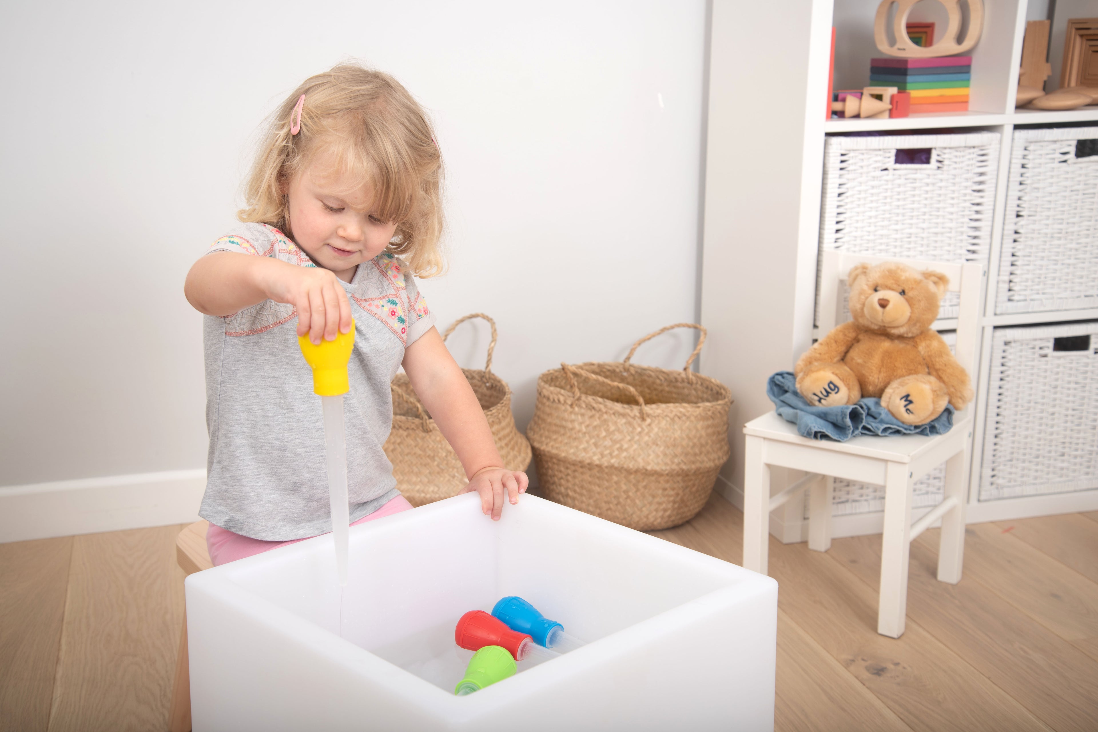 Measuring pipettes set in use: child pours from yellow pipette into white tub