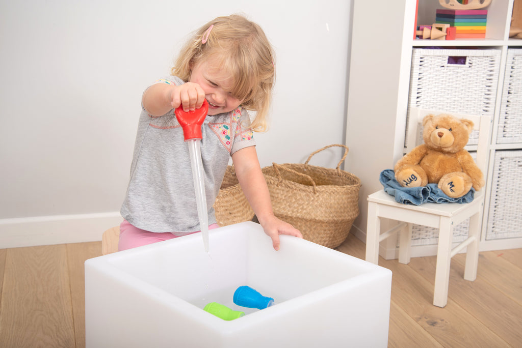 Measuring pipettes set in use: red pipette filling white tub with colored blocks