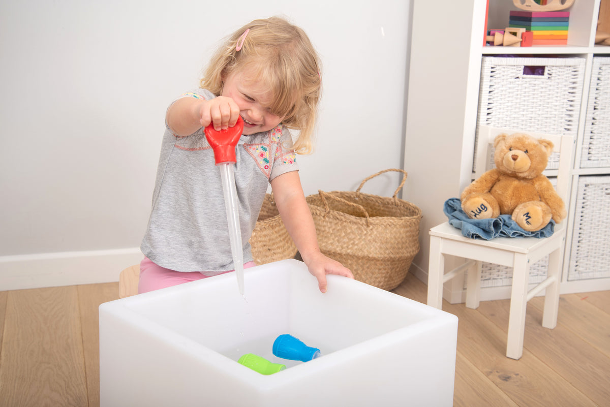 Measuring pipettes set in use: red pipette filling white tub with colored blocks