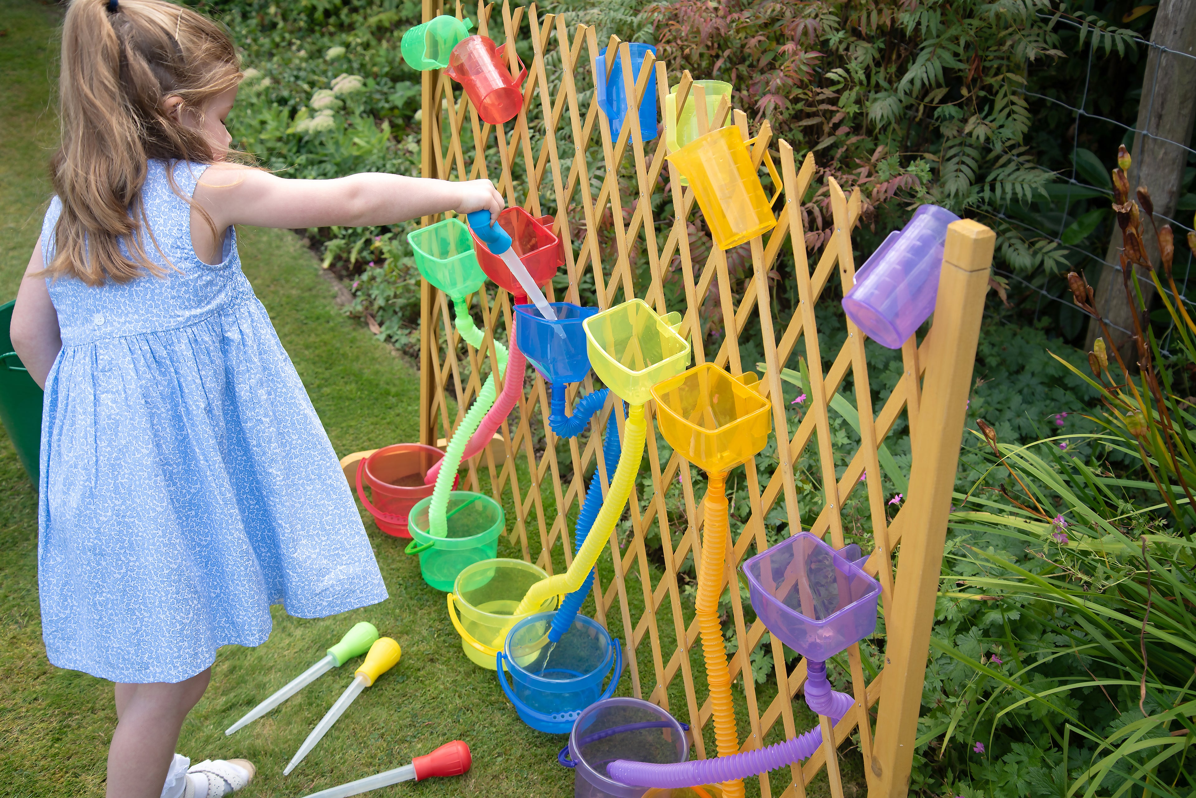 Measuring pipettes set in use: child pours with colored pipettes into garden hanging cups