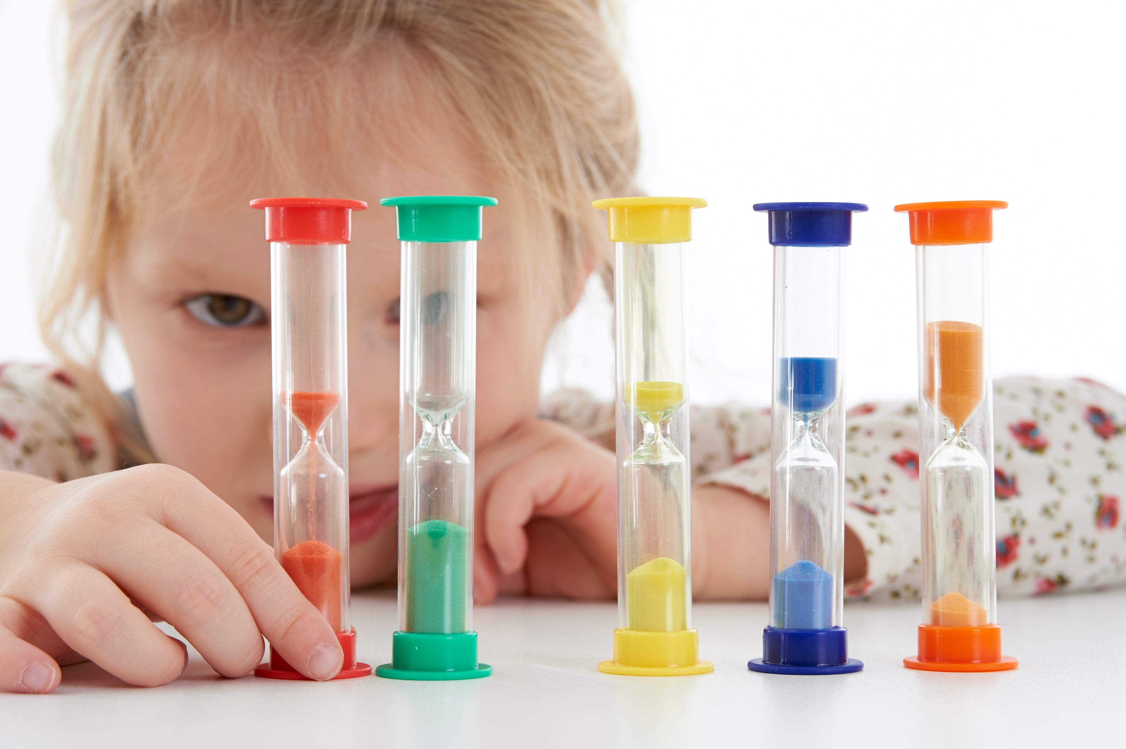 Set of five mini sand timers with colored top caps, clear glass tubes, held by child