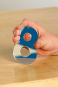 Mirror number ornament pieces with blue backing and chrome finish, held in hand