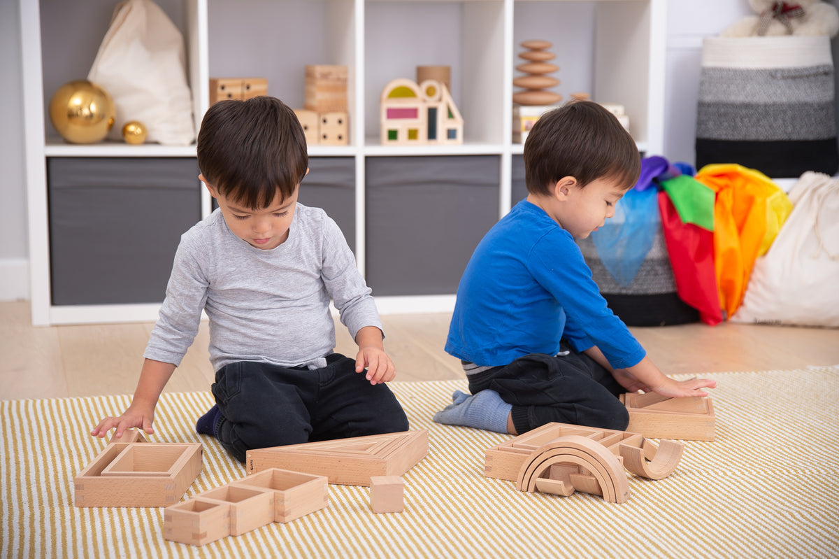 Wooden block set on play mat while kids arrange building pieces