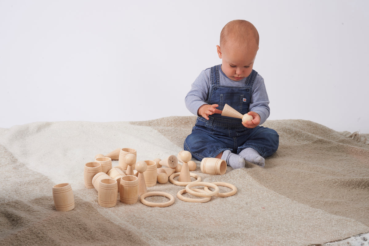 Natural wooden peg figures and ring pieces arranged on a light fabric play mat