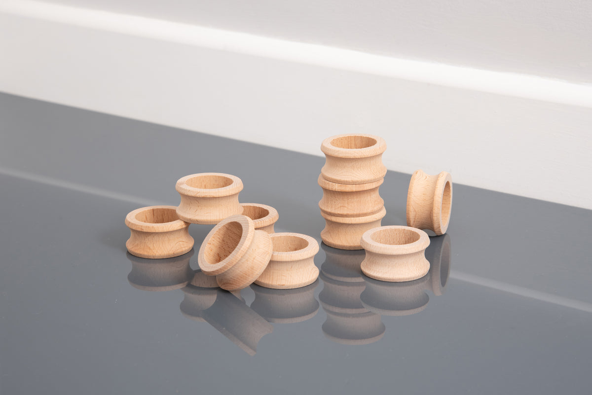 Natural wooden napkin rings on reflective surface, assorted ridged open rings