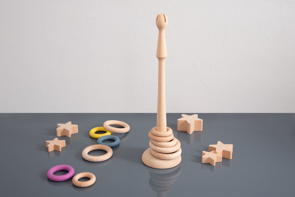 Light wooden ring stand with stacked base; surrounded by colorful ring loops and star charms