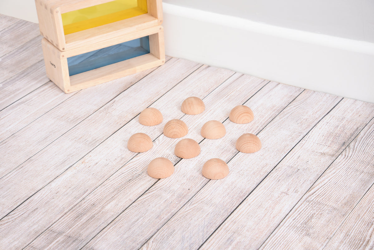 Natural wooden semispheres, light tan domes scattered on pale wooden floor