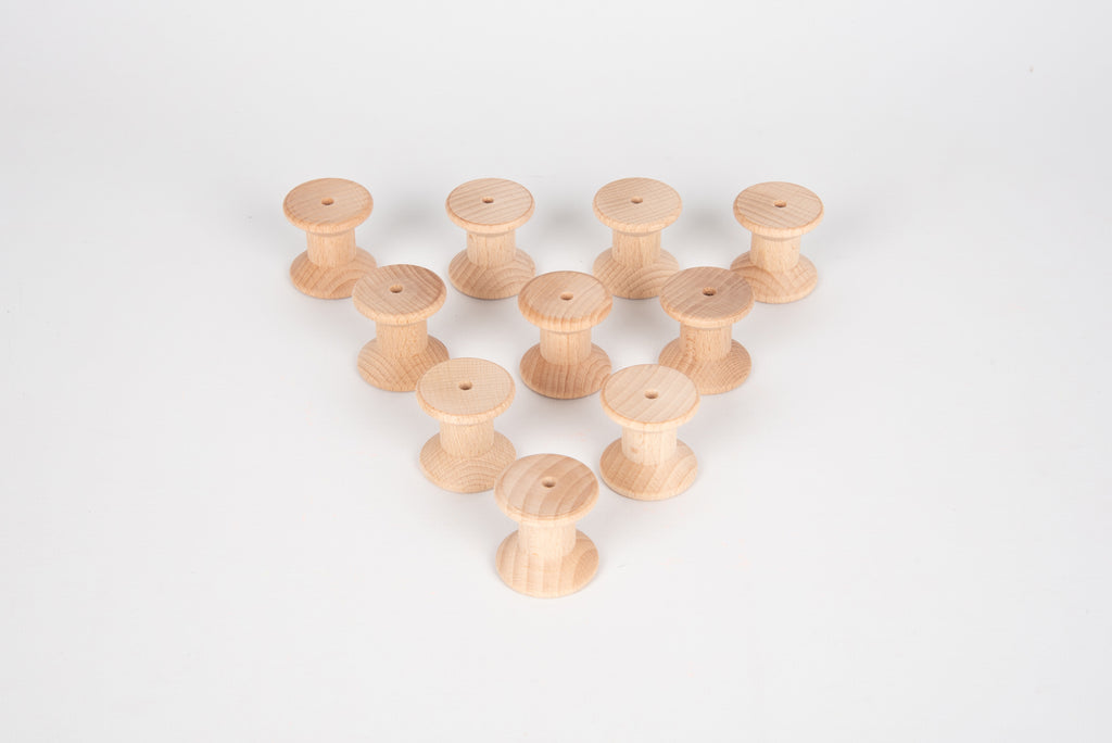Natural wooden thread spools in a small pyramid-like pile, tops facing upward.