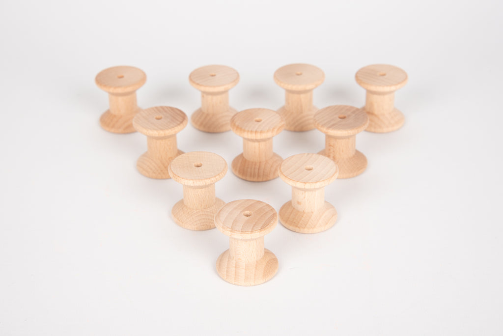 Natural wooden thread spools arranged in a loose cluster, each with a hole.